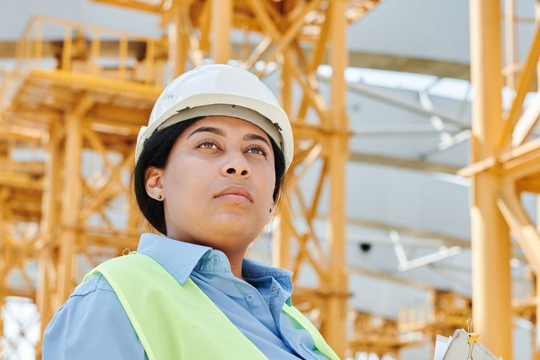 Técnica de segurança do trabalho de capacete e colete avaliando a obra